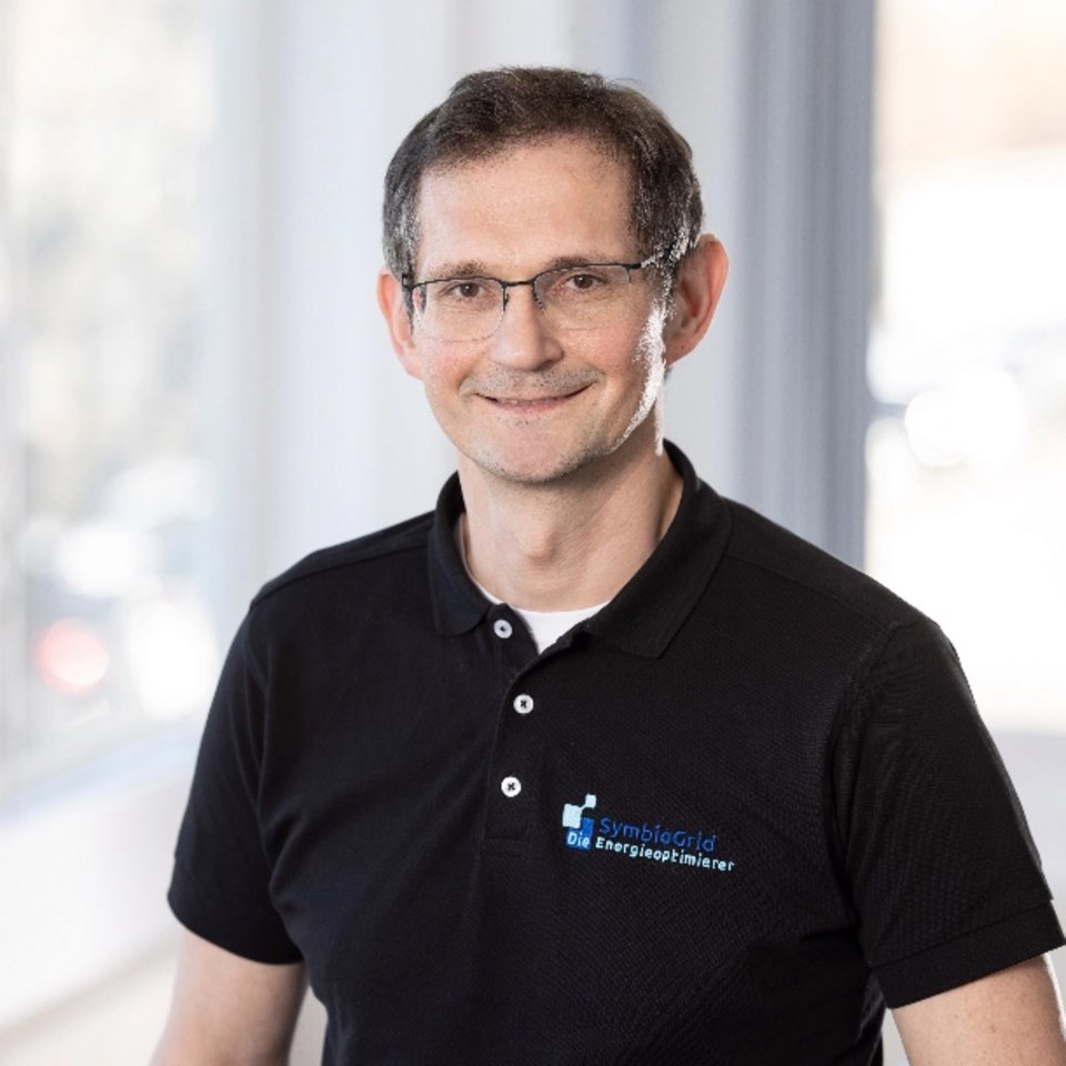  Porträt von Adam Bomba, technischer Experte bei SymbioGrid, mit schwarzem Polo-Shirt