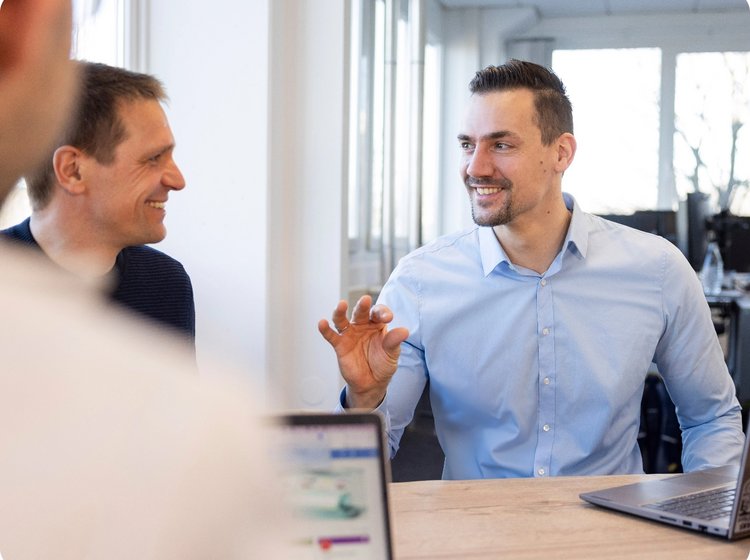 Zwei Mitarbeiter in einem Business-Meeting, gestikulierend im Gespräch über Energielösungen